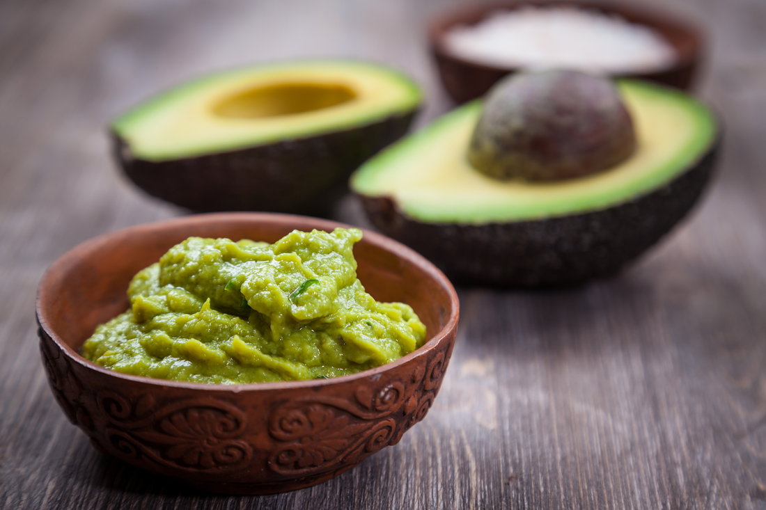 Avocado dip and avocados on a table