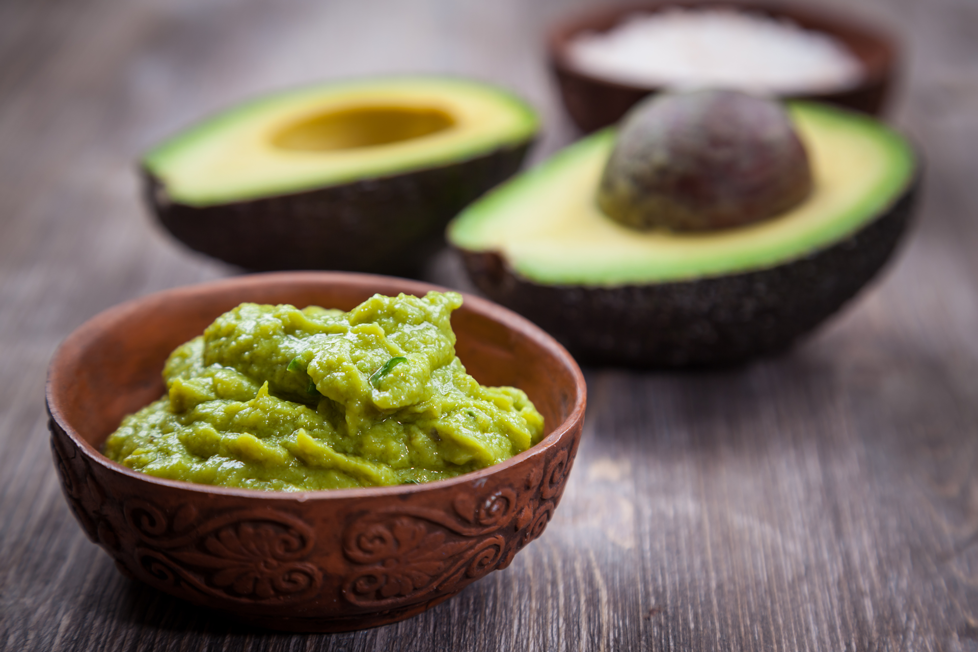 Avocado dip and avocados on a table